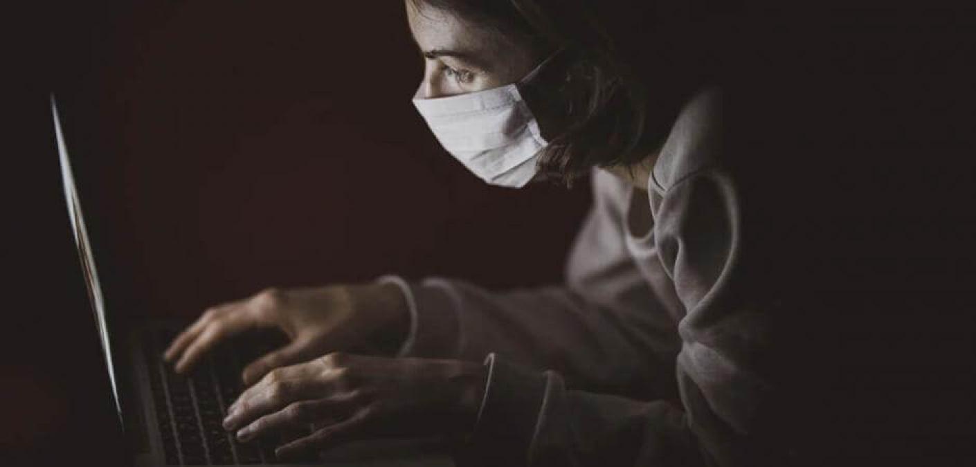 woman wearing surgical mask using computer