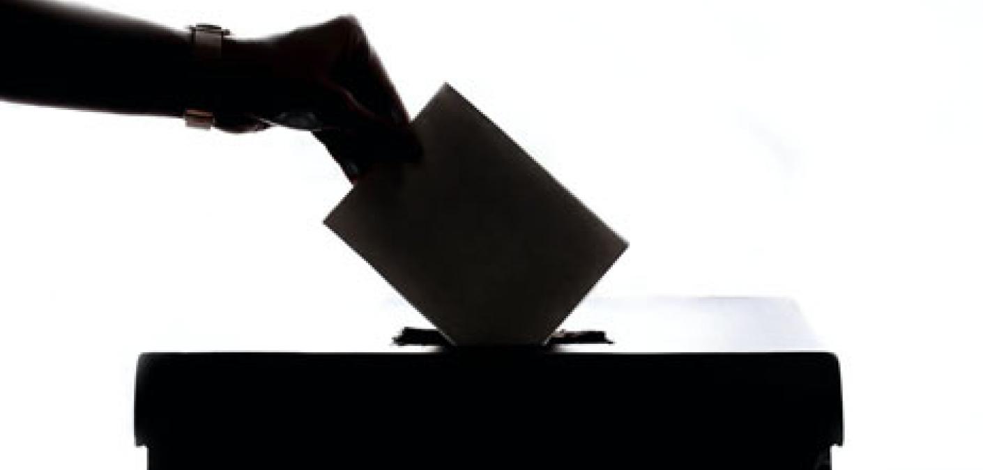 person placing ballot in box