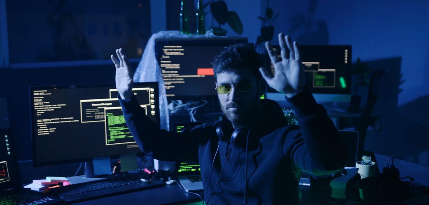 man next to computer with hands in air