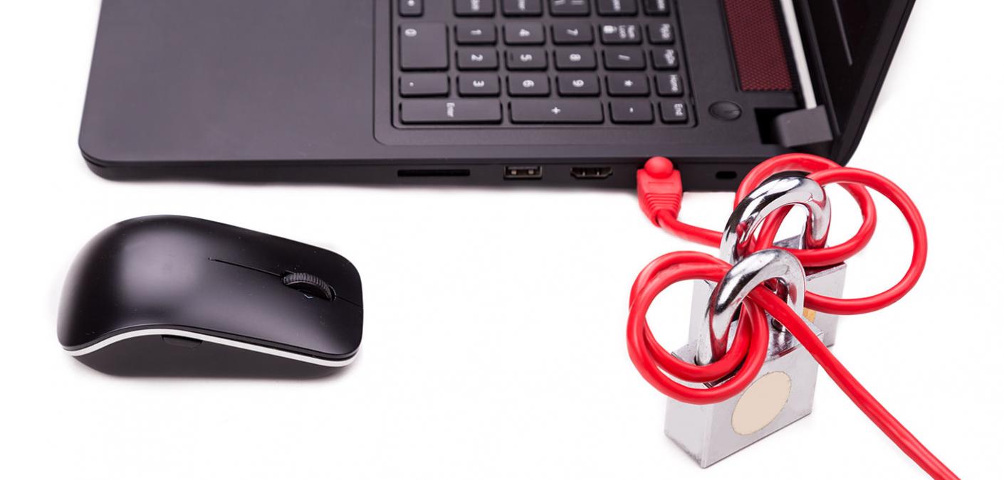 laptop and mouse with wires tangled around a padlock