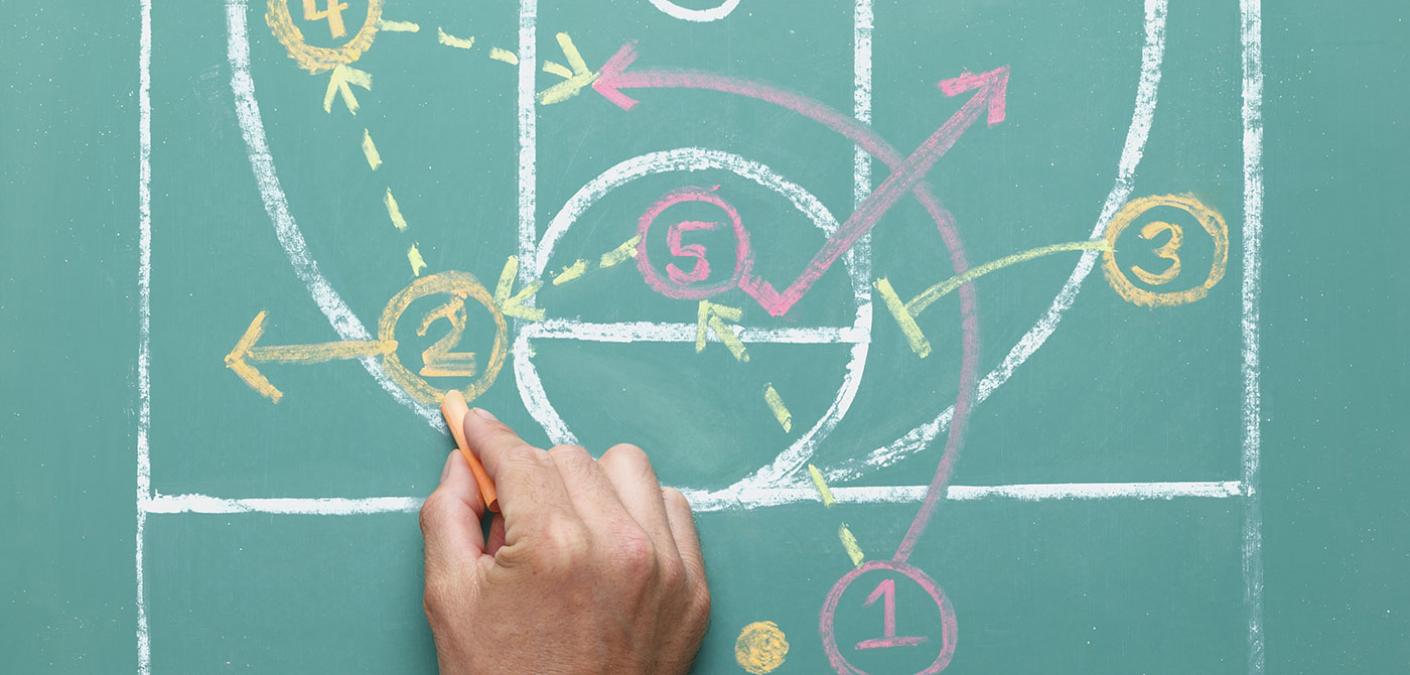 person drawing a sports play on a chalkboard